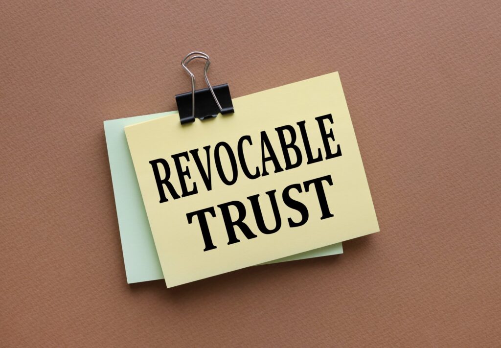 Revocable trust text on yellow sticker with clip. on a dark background. brown