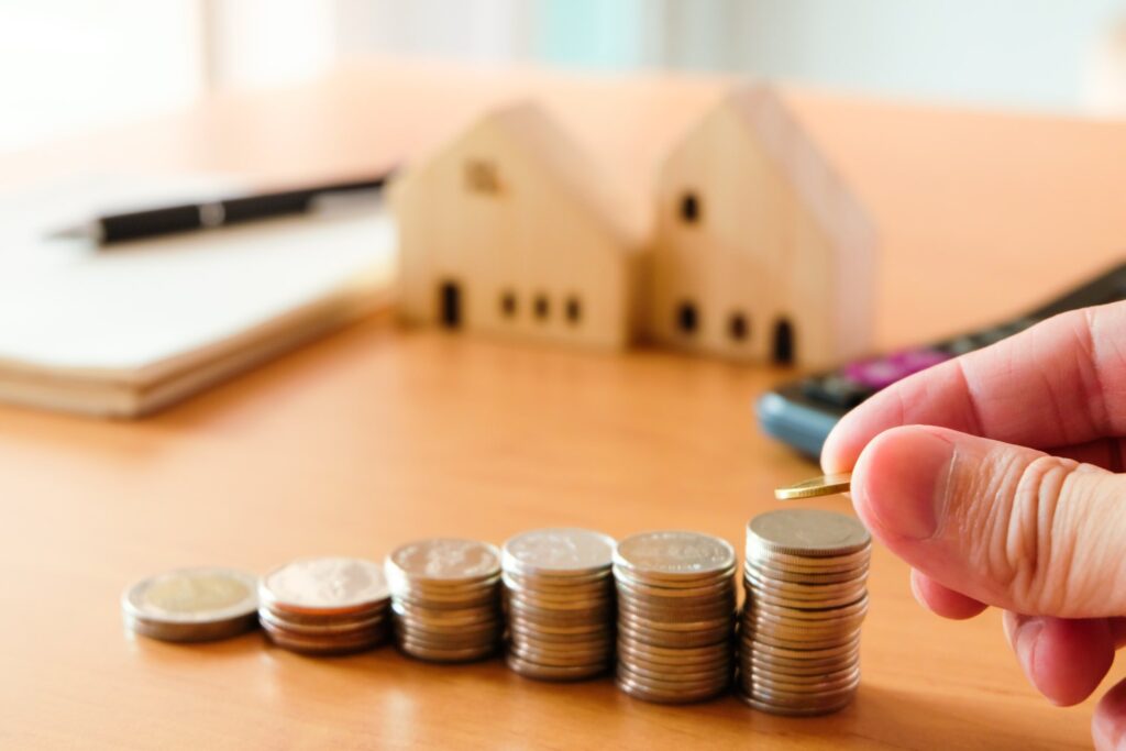 Notebook and wooden houses in the background of stacked change